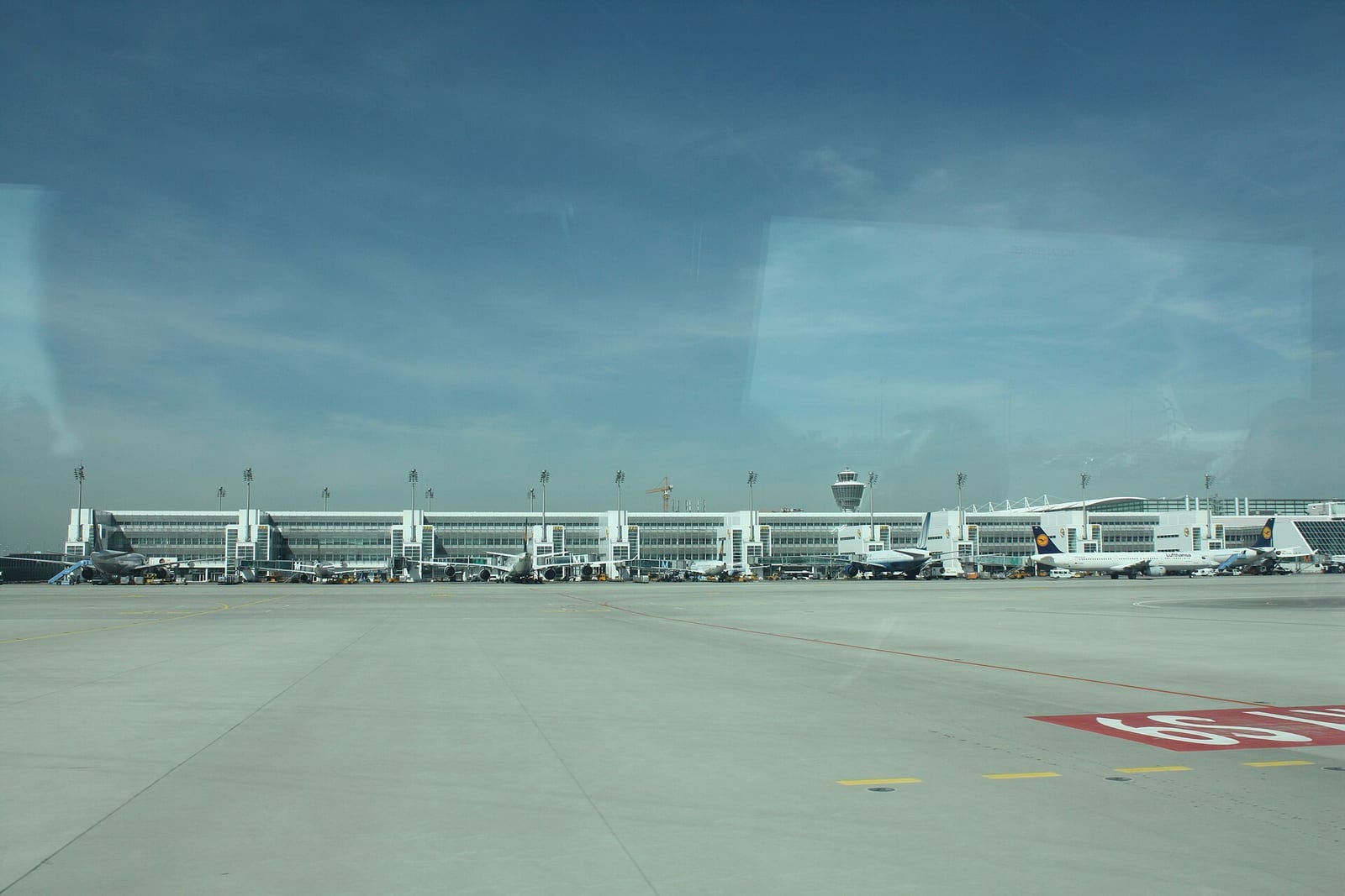 Aircraft parked at Munich Airport's Terminal 2 gates, its control tower rising behind the apron