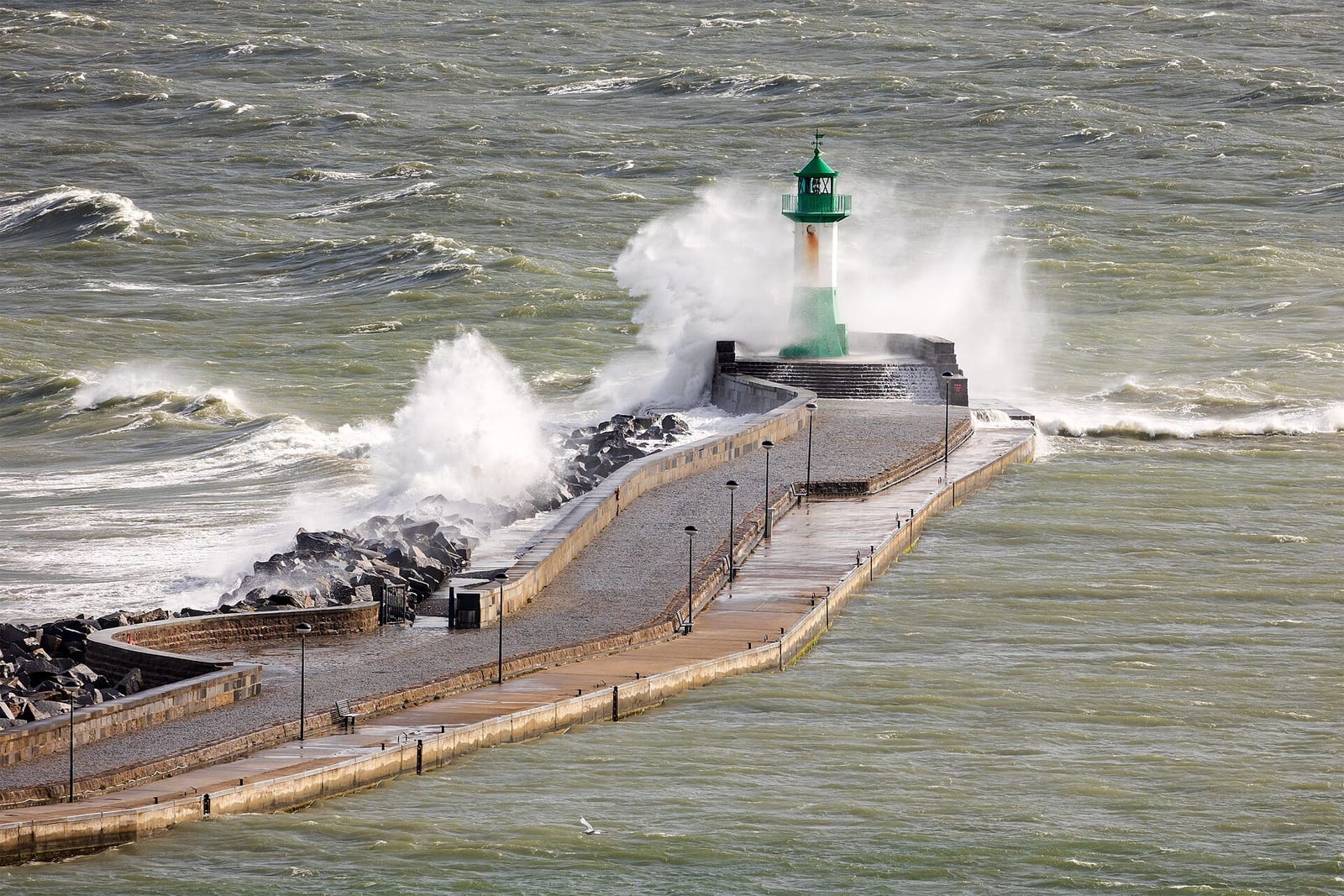 Waves break over Sassnitz's harbor mole and its green-and-white lighthouse on the Baltic