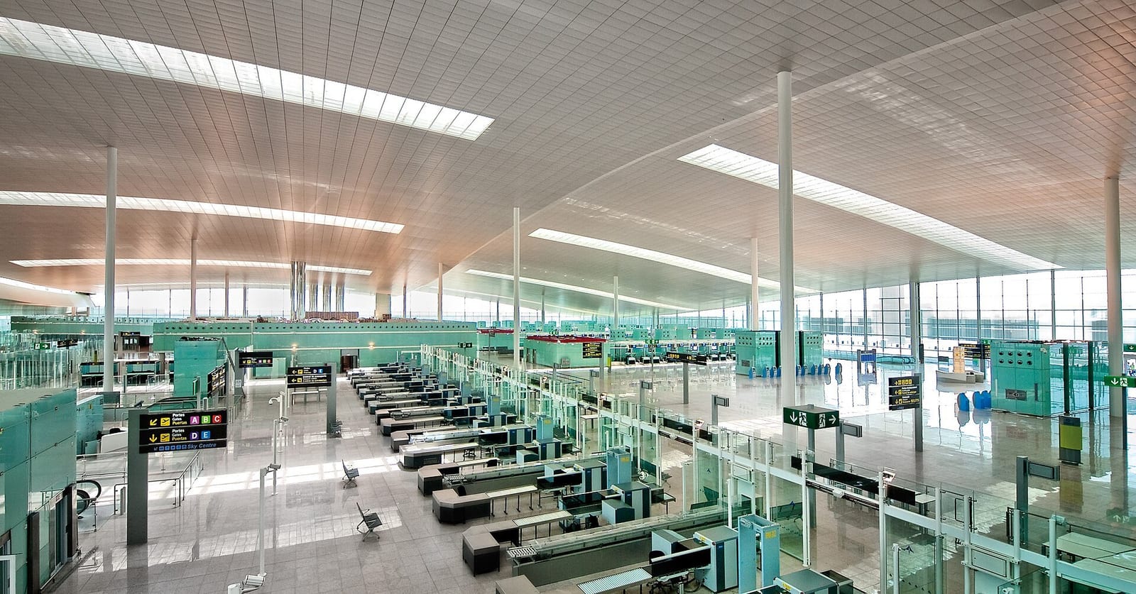Rows of empty security lanes stretch across Barcelona airport's glass-walled Terminal 1 hall