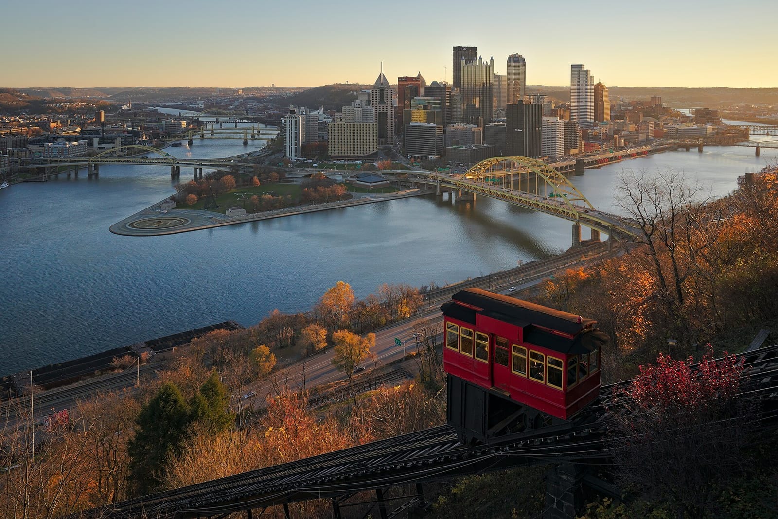 Pittsburgh's downtown skyline sits at the point where two rivers meet, seen from a hillside overlook.