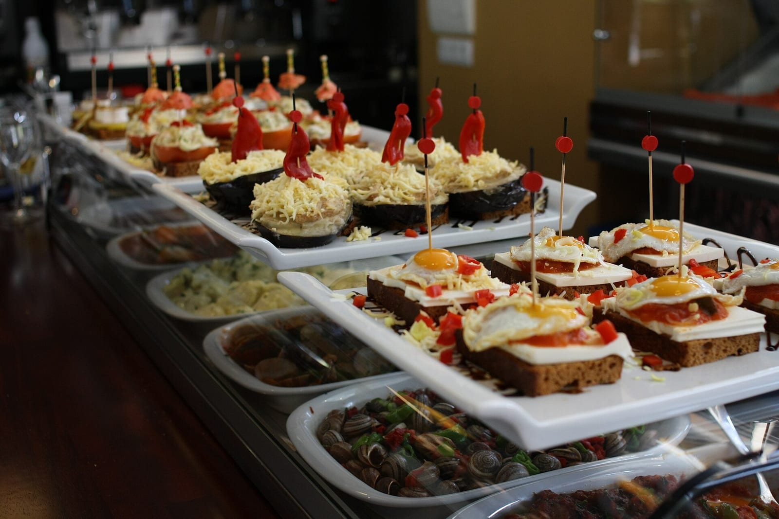 A tapas bar counter lined with skewered pintxos plates, ready to be served