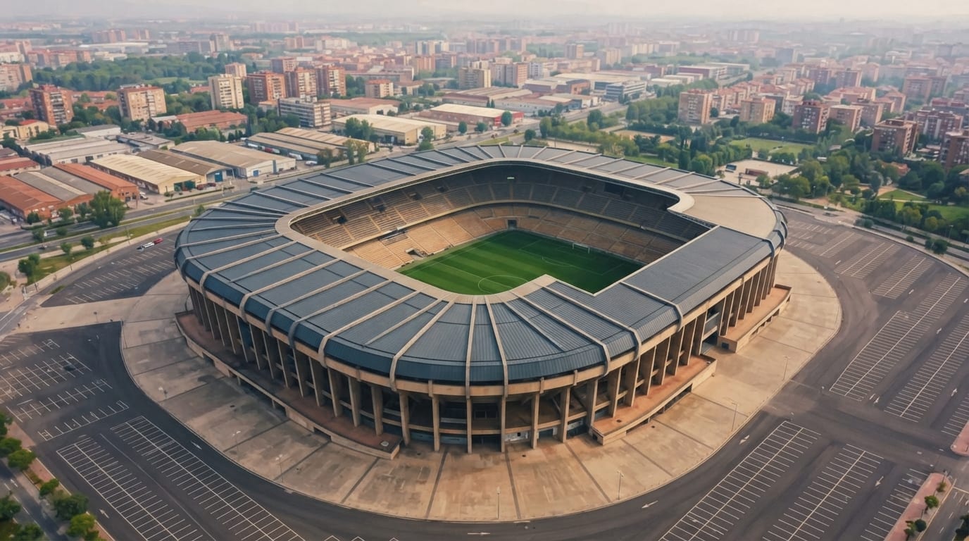 A stadium roof rings a green pitch, wide empty parking lots stretching into hazy sprawl