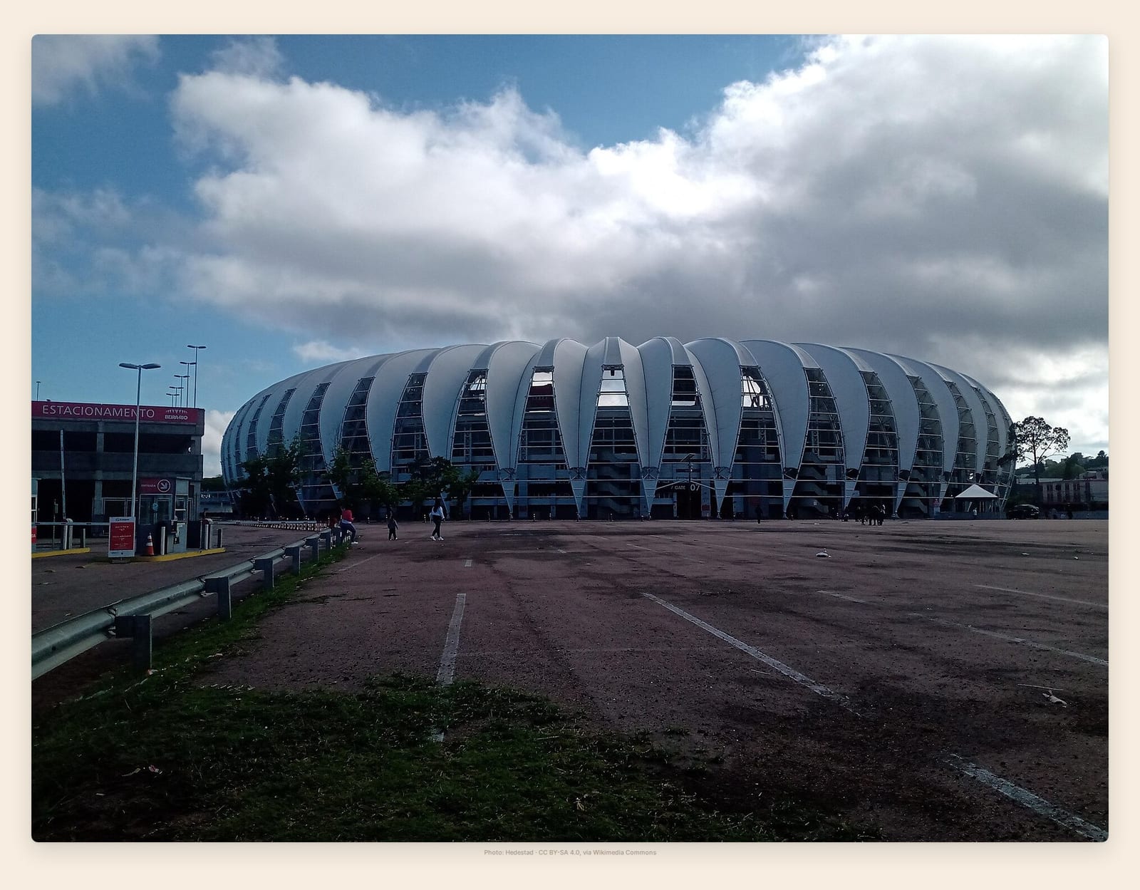 Beira-Rio's ribbed white roof curves upward like overlapping petals against a heavy, cloud-piled sky
