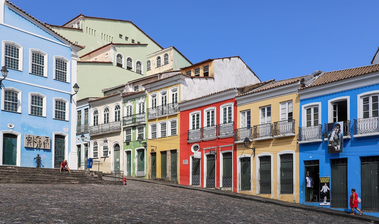 A row of blue, ochre and red colonial townhouses lines Pelourinho's steep cobblestone plaza in Salvador