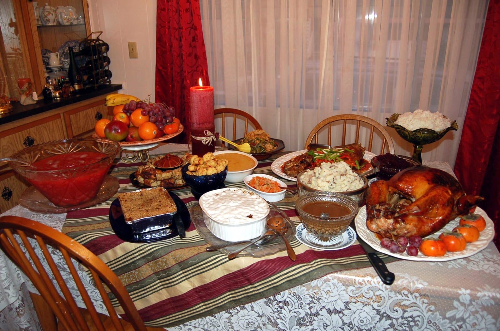 Turkey, stuffing, and sides crowd a shared Friendsgiving table set for a group of friends.