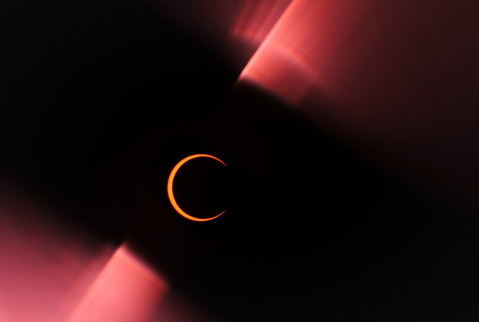 A blazing ring of orange sunlight glowing around the moon at an annular eclipse's peak