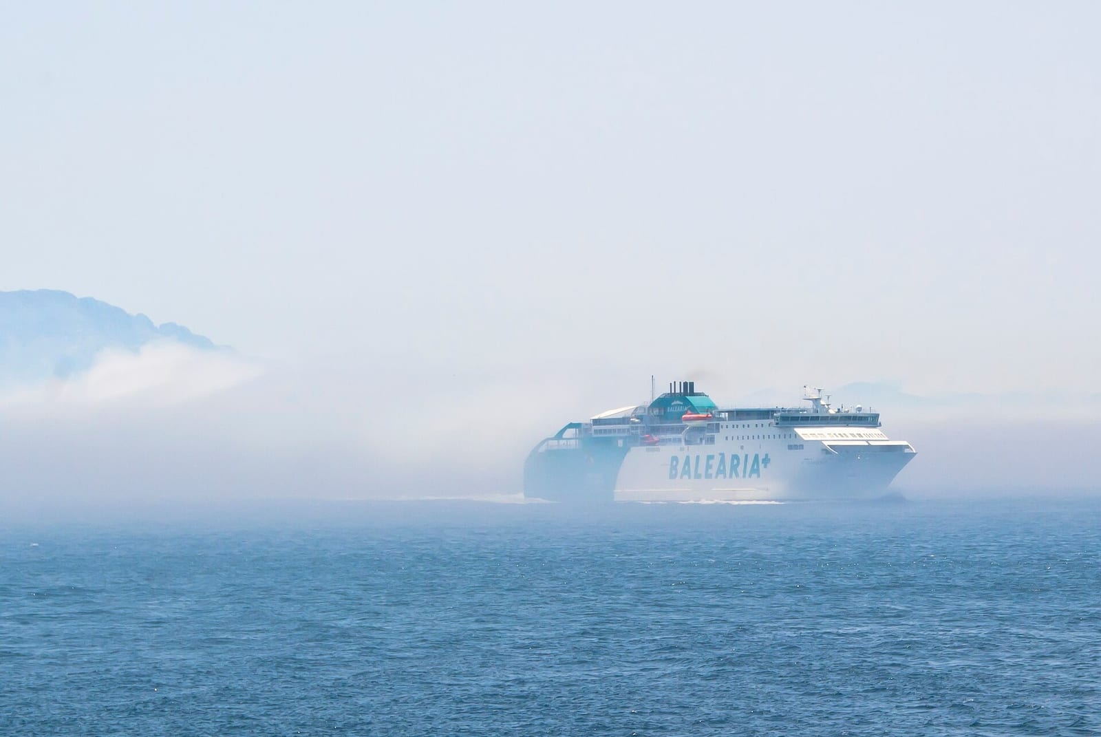 A Baleària fast ferry on the Ceuta to Algeciras crossing, sailing out of low sea mist in the Strait