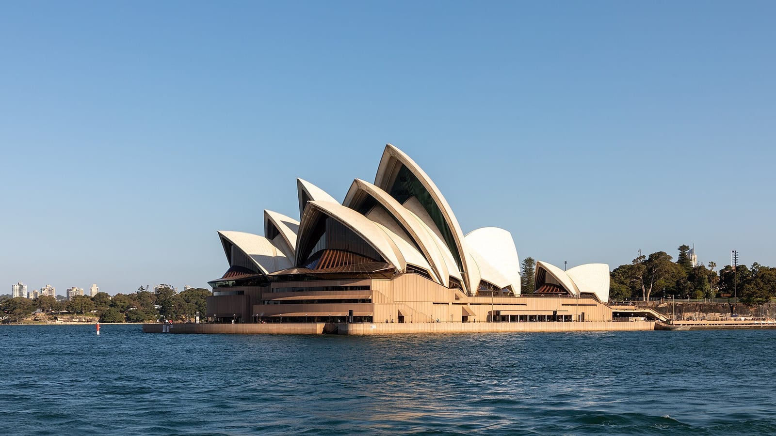 The Sydney Opera House's white sails beside the harbour on a clear afternoon