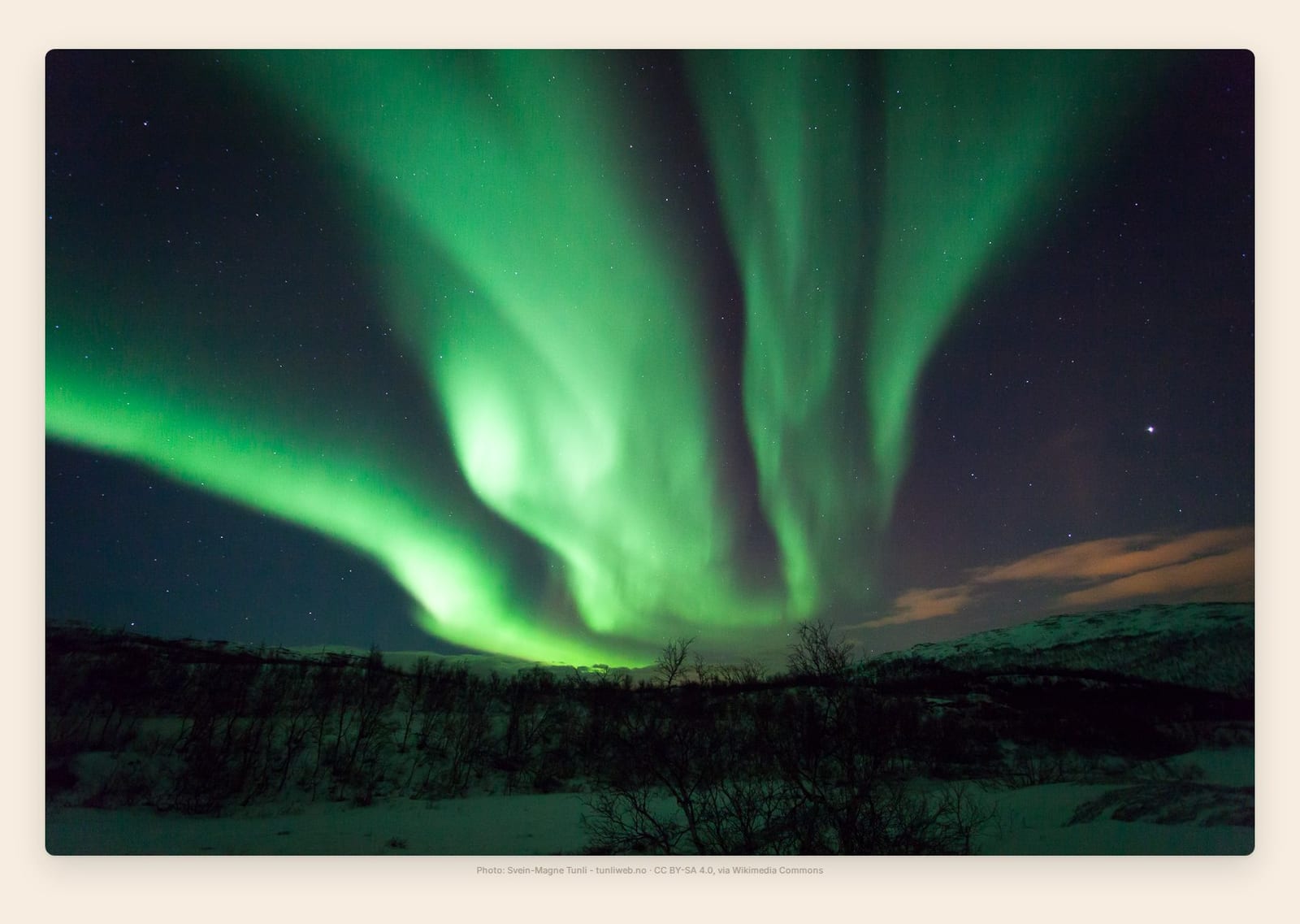 Green and violet aurora curtains ripple over the fjord near Tromso, Norway