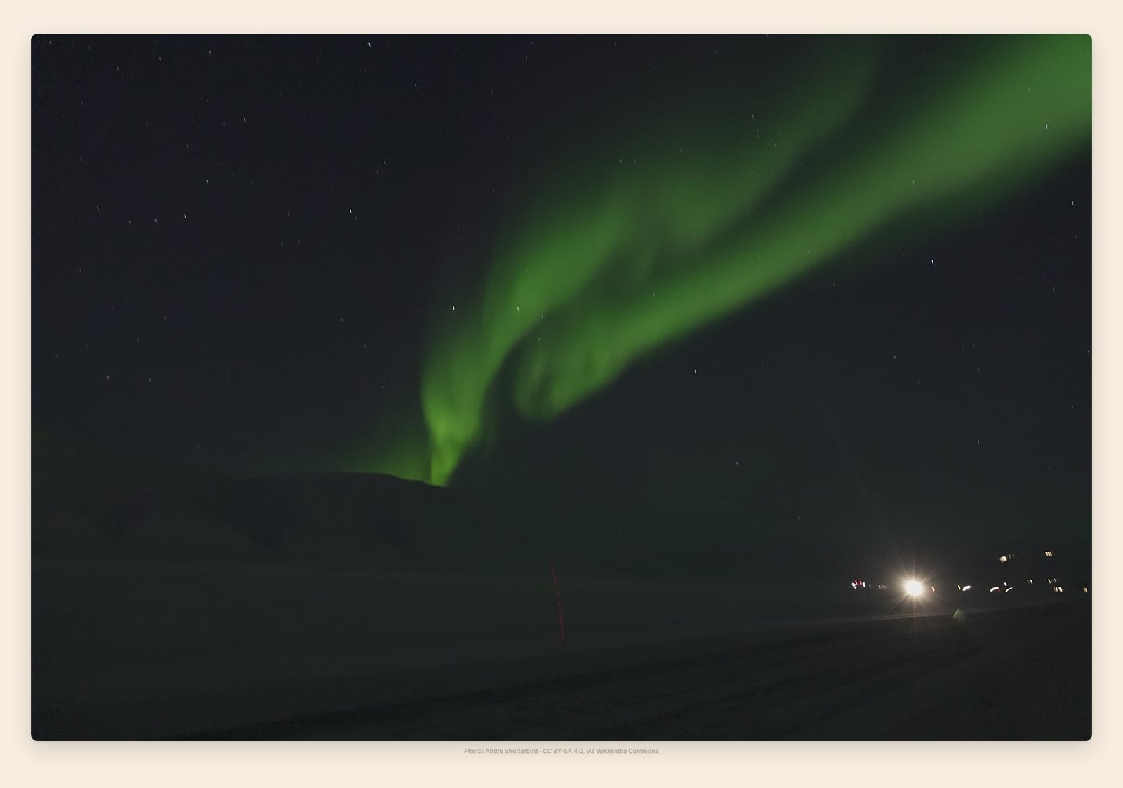 Aurora ribbons stretch across the dark valley of Adventdalen, minutes from Longyearbyen
