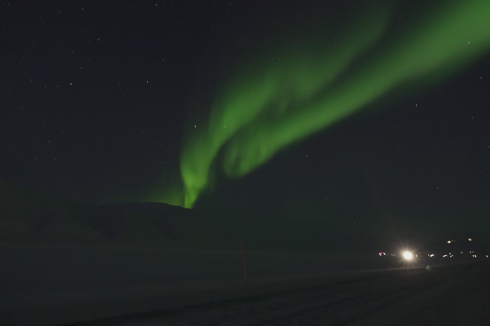 Aurora ribbons stretch across the dark valley of Adventdalen, minutes from Longyearbyen